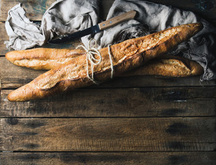 French baguettes on rough rustic wooden background. Top view, copy space