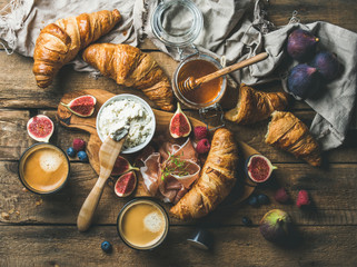 Breakfast with freshly baked croissants, ricotta cheese, figs, fresh berries, prosciutto, honey in...
