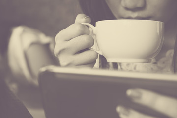 Young asian girl drinking coffee and using smartphone in black and white