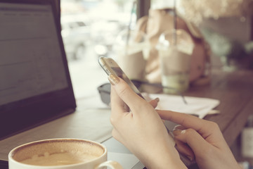 Young woman hand holding using smartphone and laptop