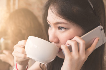 Close up Young teen asian girl drinking coffee and using smartphone