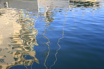 Abstract reflections of boats and buildings in blue rippled water
