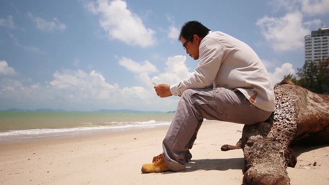 Oil man to relaxing and use smart phone take a photo on the beach ocean and blue sky 