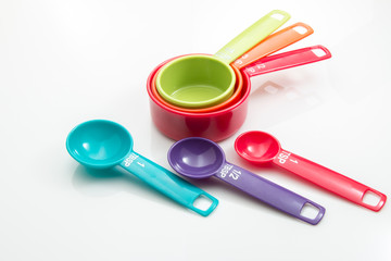 Plastic measuring cups and spoons on a white background.