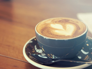 Cappuccino coffee in black cup on wooden table, Soft focus, Summ