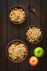 Englische Apfel Crumble oder Crisp, eine gebackene Süßspeise aus Apfel und Haferflocken Streusel, fotografiert auf dunklem Holz mit natürlichem Licht