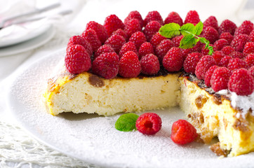 Cheesecake, souffle, cream mousse, pudding dessert with fresh raspberries and mint leaves on a white plate