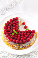 Cheesecake, souffle, cream mousse, pudding dessert with fresh raspberries and mint leaves on a white plate