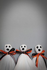 Halloween concept background : Three halloween ghosts DIY made from white tissue paper, black and orange ribbon on gray background