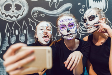 Three girls going on Halloween, grimace make selfie  a dark background with  pattern