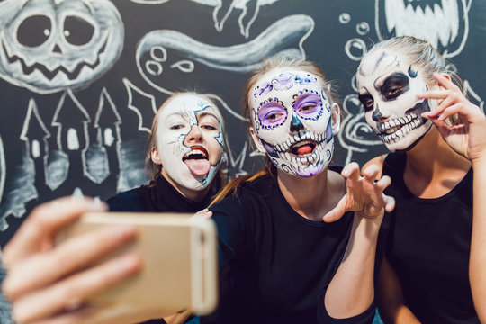 Three girls going on Halloween, grimace make selfie  a dark background with  pattern
