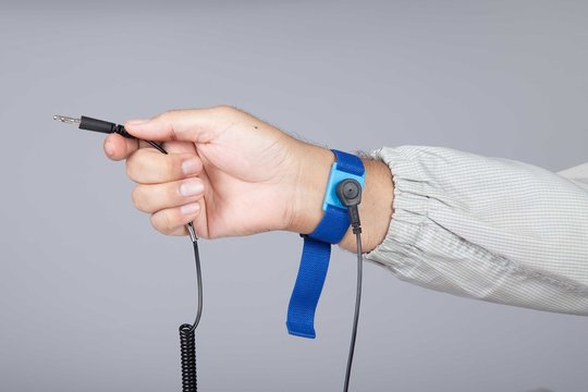 Ground bracelet on man hand  wearing ESD cloth isolated on gray