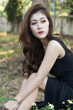 Beautiful asian woman in black dress sitting in the garden.