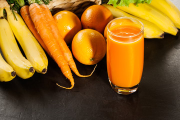 Glass of fruit juice with orange, carrots and banana
