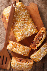 Freshly baked pie stuffed with cabbage and sausages closeup. vertical top view
