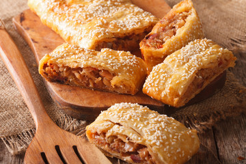 Tasty puff pie stuffed with cabbage and sausages closeup. Horizontal
