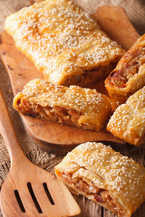 Delicious puff pie stuffed with cabbage and sausages closeup. vertical
