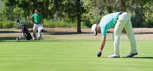 Obraz premium Golfer and caddy on the putting green