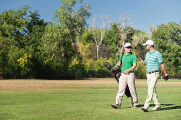 Friends playing golf, walking down the fairway