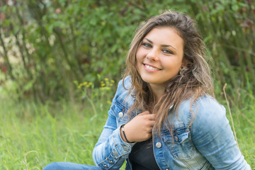 Portrait of laughing head tilted back teenage girl sitting outdoors. Girl is looking at the camera. 