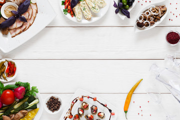 Variety of snacks for traditional tableful, free space. Delicious homemade meals with glass decanter with vodka on white wooden background, flat lay, copy space, frame