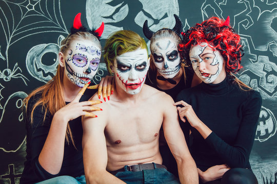 Three girls and a guy with Halloween face art on  dark background  pattern