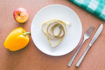 Empty plate, fork, knife and tape measure on wooden table - Heal