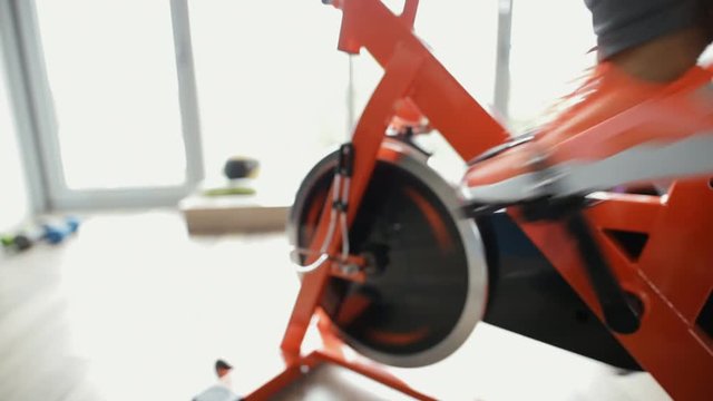 Female foot rotate exercise bike in gym - cropped motion