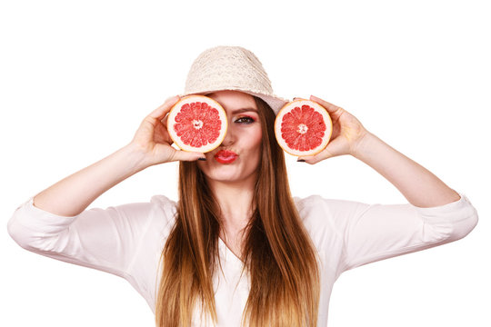 Girl covering eyes with two halfs of grapefruit citrus fruit