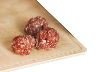 Raw meatballs on a wooden board. Isolated