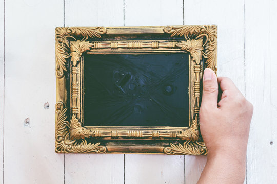 Hands holding  picture frame on wooden background