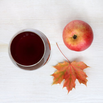 taste of autumn/ flat lay of apple, maple leaf and a glass of wine on a light surface top view 
