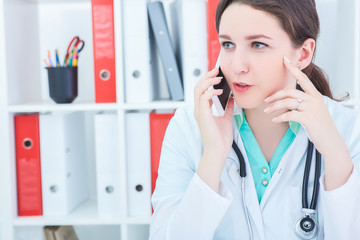 Closeup portrait of a young confident female doctor talking on the phone with patient. Remote health care concept.