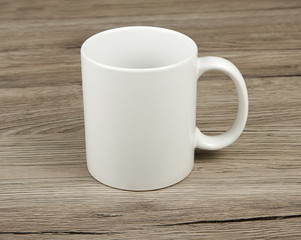 White cup on a wooden background.
