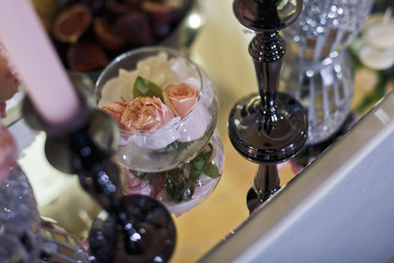 Black candleholders stand on mirror with a glass bowl