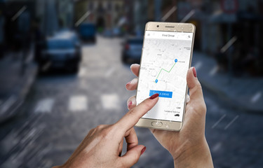 Taxi, drive hare app on smartphone display in woman hand. City street in background.