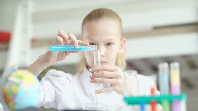 Serious teen girl studying chemistry. Girl holding flask with blue chemical solution. Chemicals for children. Lessons chemistry. Girl doing chemistry experiment