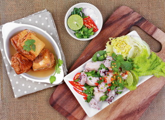 Gold bar soup as fried tofu wrap minced pork in soup served with spicy and sour mixed herb salad with squid wrap minced pork . 