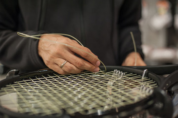 Stringing Machine. Close up of tennis stringer hands doing racket stringing in his workshop