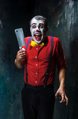 The scary clown holding a knife on dack. Halloween concept