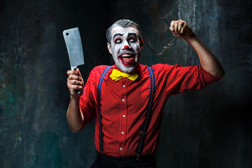 The scary clown holding a knife on dack. Halloween concept