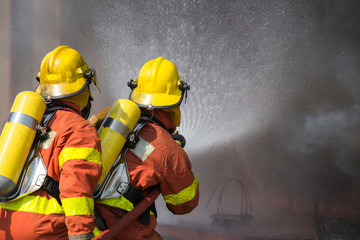 2 firefighters spraying water in fire fighting operation