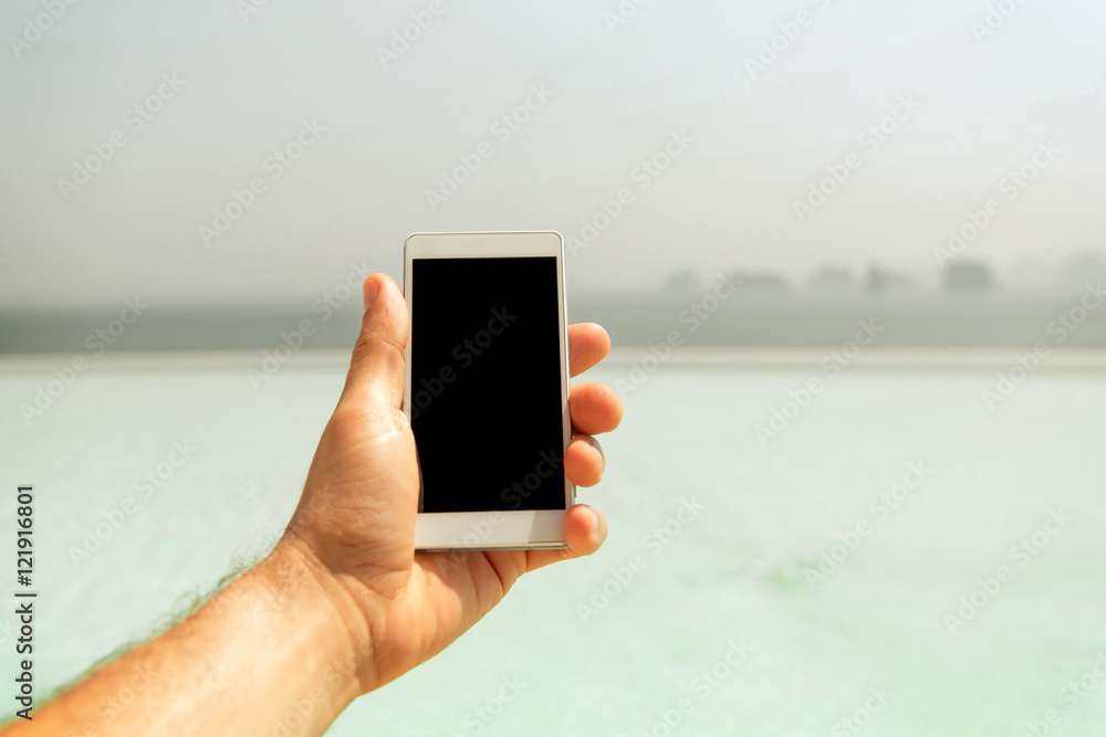 Poster close up of male hand holding smartphone on beach