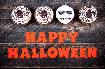 Halloween background. Funny pumpkin cupcakes with spiders and scull for halloween party on old rustic wooden table