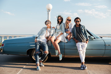 Happy young friends standing near cabriolet