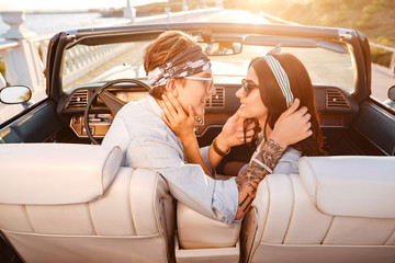 Happy couple sitting and kissing in cabriolet in summer