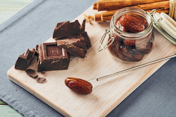 Chocolate, date fruit and cinnamon on a white chopping board on a blue table. Pastel colors
