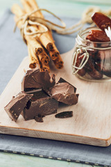 Chocolate, date fruit and cinnamon on a white chopping board on a blue table. Pastel colors