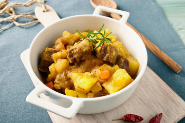 Sicilian stew in a white pot on a blue table, pastel color