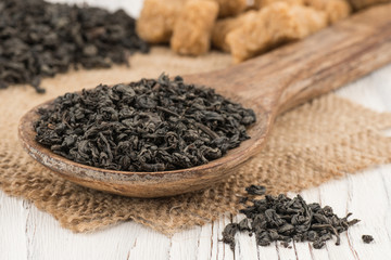 Black tea in a wooden spoon and an old white table.
